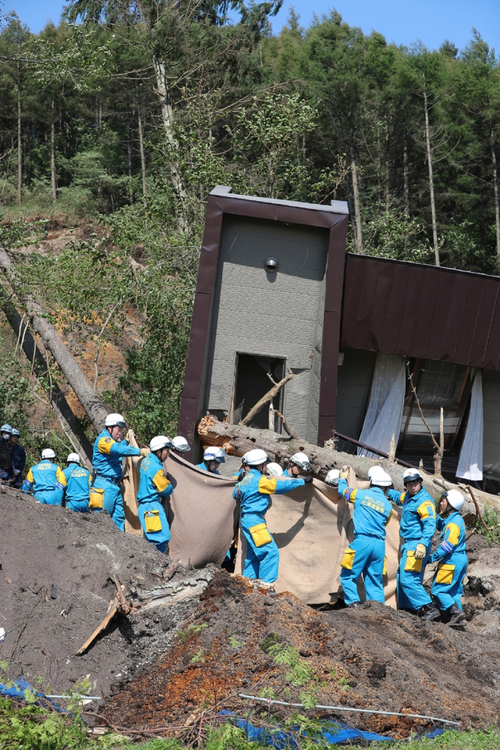 Equipes de resgate carregam o corpo da vítima de uma área atingida por deslizamentos de terra na cidade de Atsuma (Foto: AFP PHOTO / JIJI PRESS / JIJI PRESS / Japan OUT)