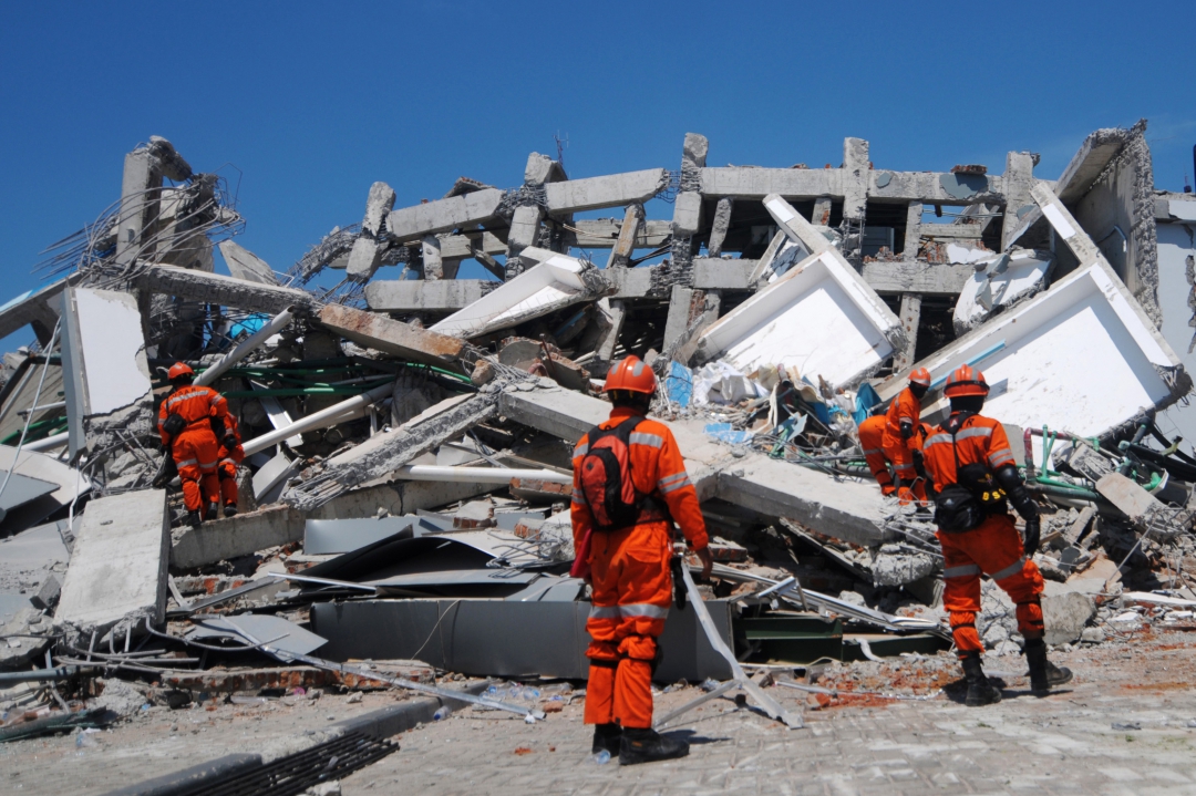 Membros de uma equipe de resgate da Indonésia buscam sobreviventes de um prédio em Palu (Foto: AFP PHOTO / Jewel SAMAD; Ola Gondronk; Adek BERRY; Mohd RASFAN)