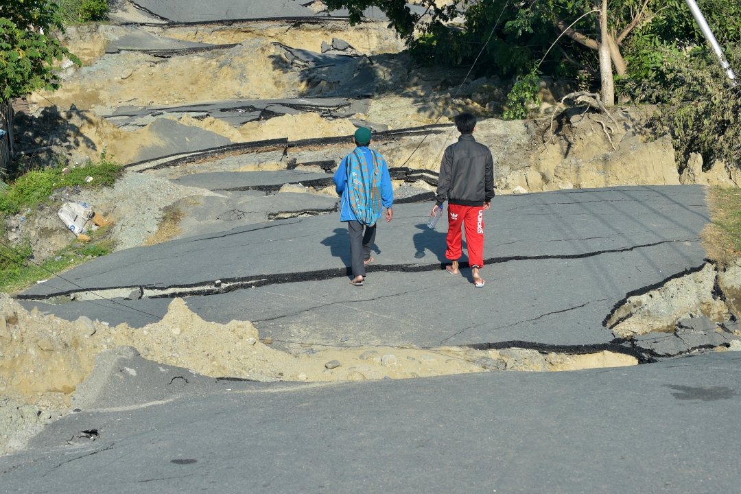 Pessoas caminham por estrada danificada em Palu (Foto: AFP PHOTO / Jewel SAMAD; Ola Gondronk; Adek BERRY; Mohd RASFAN)