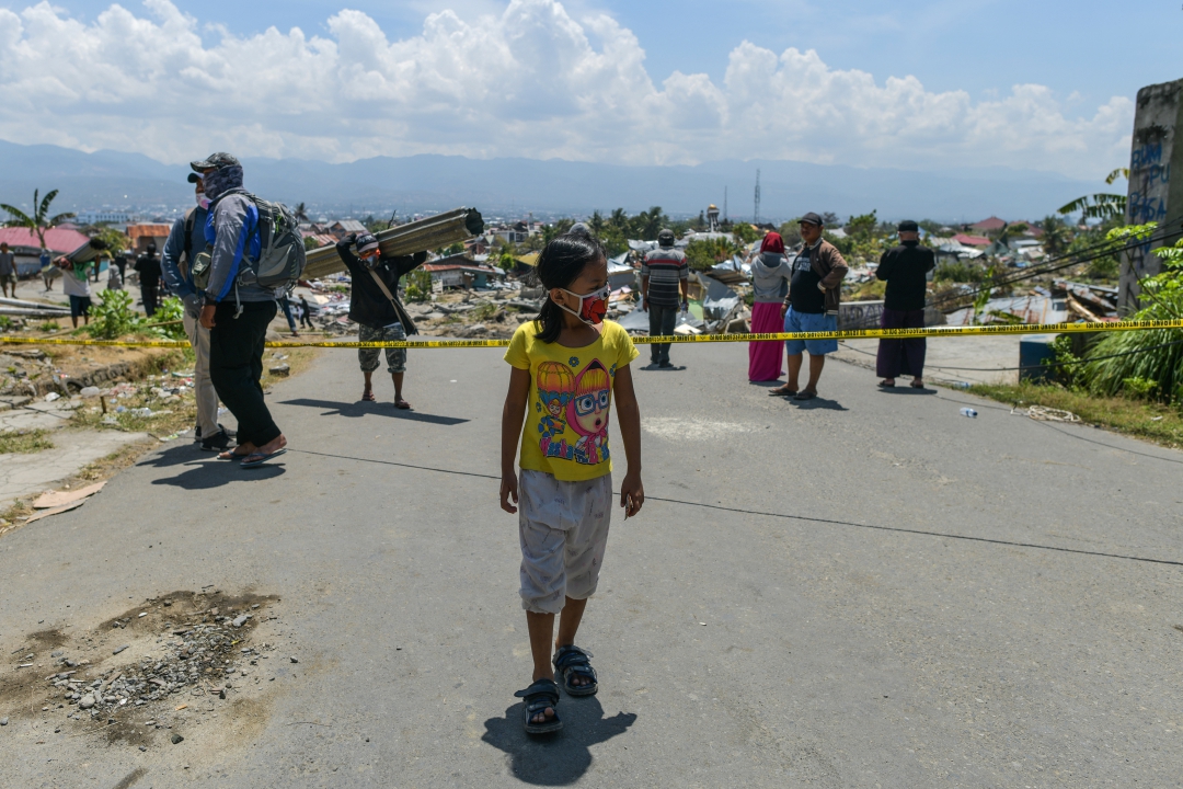 Uma garota usando uma máscara passa por escombros na aldeia Perumnas Balaroa
(Foto: AFP PHOTO / Jewel SAMAD; Ola Gondronk; Adek BERRY; Mohd RASFAN)