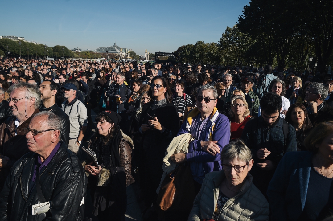 Pessoas acompanham homenagem ao cantor por tela gigante em Paris (Foto: AFP PHOTO / LUCAS BARIOULET; Ludovic MARIN)