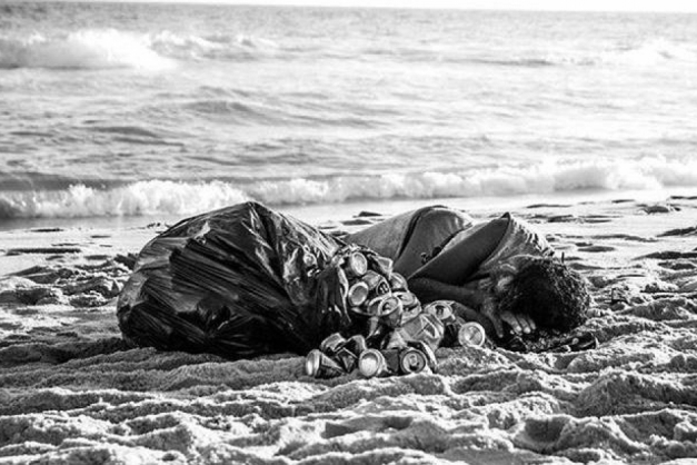 Ele escolheu as areias da praia para dormir, encostado às latas que recolheu (Foto: Maria Eduarda José)