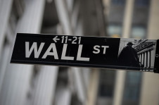 Placa indicando a Wall St. em frente ao pr&eacute;dio da bolsa de valores de Nova York