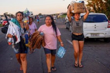 Pessoas caminham carregando itens doados em Eldorado do Sul, no Rio Grande do Sul