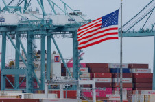 Bandeira dos EUA tremula perto de contêineres enquanto um navio é descarregado no Porto de Los Angeles, em San Pedro, Califórnia