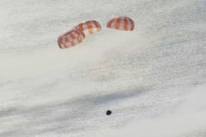 Tr&ecirc;s paraquedas principais s&atilde;o acionados na c&aacute;psula tripulada Artemis II nesta captura de tela de um v&iacute;deo ao vivo enquanto ela desce em dire&ccedil;&atilde;o ao pouso ap&oacute;s a passagem pela Lua