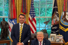 Flavio Bolsonaro e Donald Trump, que n&atilde;o levantou da cadeira para se deixar fotografar